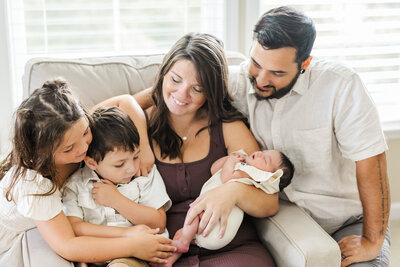 mom, dad and kids snuggling newborn baby at home session