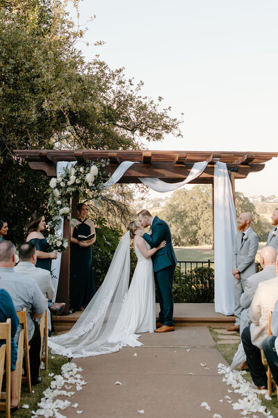Ceremony arch bride and groom kissing at catta verdera golf course