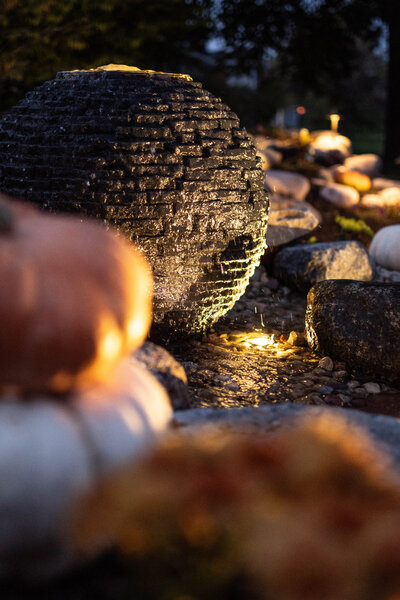 Stacked Slate Sphere fountain lit up at night with spotlights making the running water sparkle