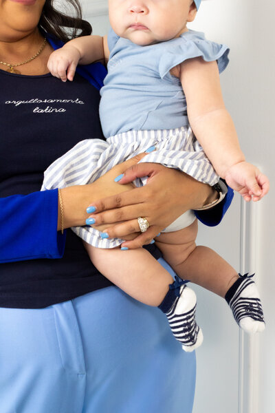 Bilingual career coach supporting moms who want to grow in their industry with confidence and balance, pictured holding her baby as a symbol of empowerment and success.