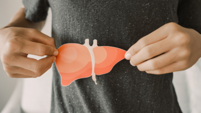 woman in gray shirt holding a paper cutout of a liver over the location of her liver