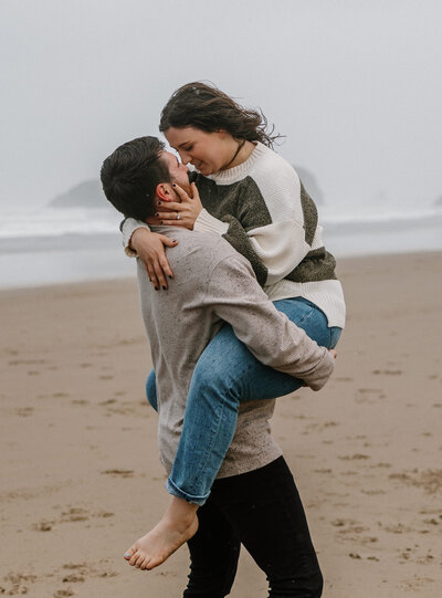 playful couple kiss in the rain on the oregon coast.