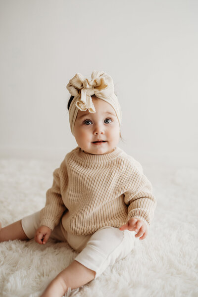 eight month old baby girl sitting on an all white background for her Colorado Milestone baby session
