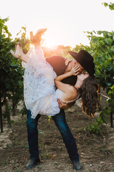Elopement Photographer, groom with cowboy hat lifts up his new bride in a vineyard