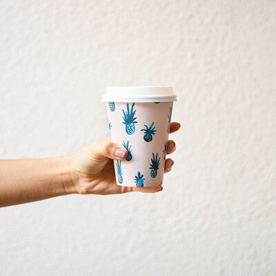 hand holding cardboard coffee cup tropical