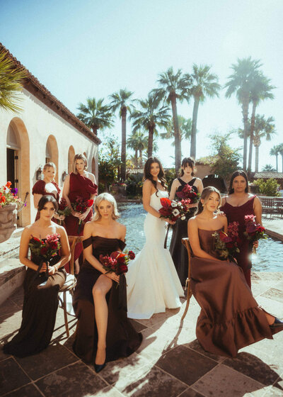 Bridal party in romantic red dresses by pool at Arizona wedding planned by Arizona wedding planner