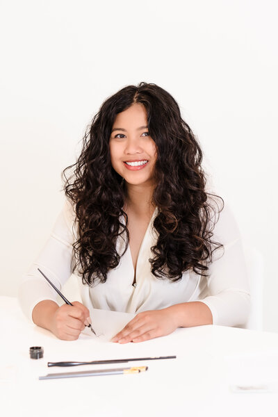 brand photo of a calligrapher posing with her tools of the trade