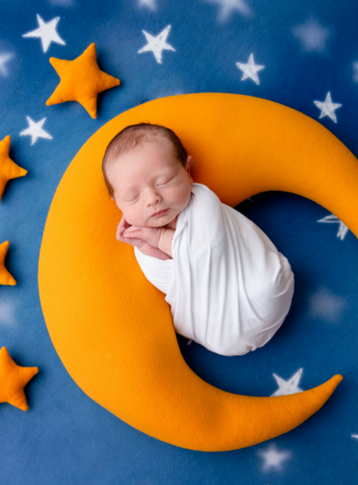 Newborn photo session with baby sleeping wrapped on top of a moon and surrounded by stars