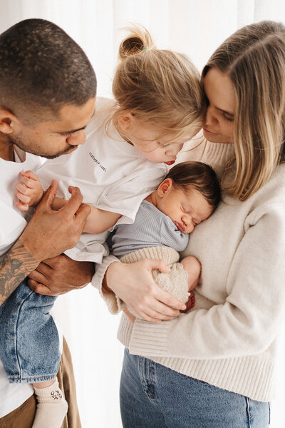 dad holding newborn with toddler