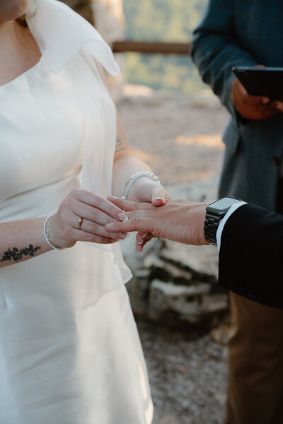 emotional elopement ceremony photo of bride putting wedding ring on groom's finger during their marriage ceremony at Petit Jean Mountain State Park in Arkansas