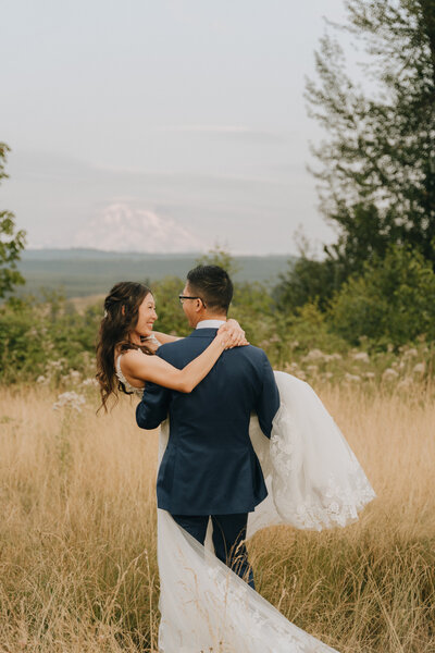 groom holding bride in front of mount rainier