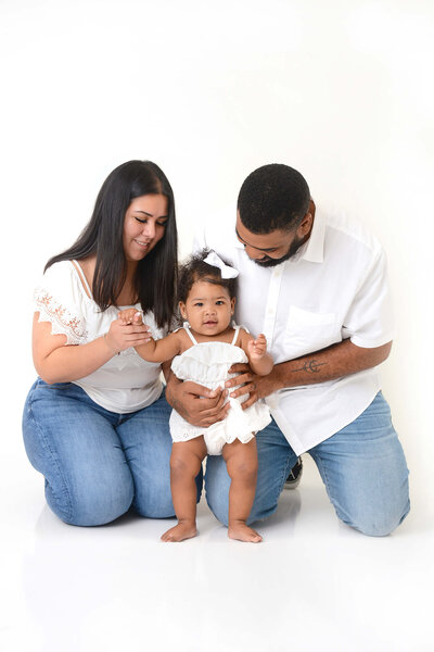 a mom and dad smile at their daughter during their family photoshoot