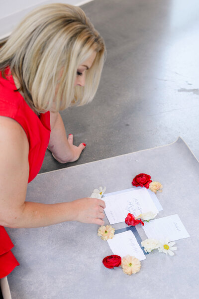 Austin wedding planner styling wedding stationery with fresh florals for a creative flat lay, highlighting attention to thoughtful details.
