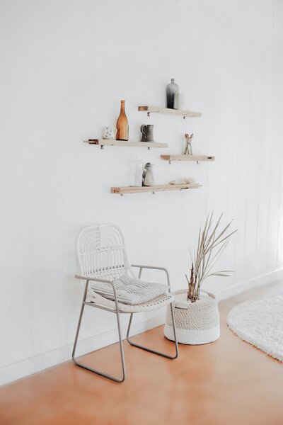 chair sitting next to plant in white room with orange floor