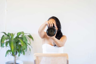 Dallas personal brand photographer posing with her professional camera inside her natural light photo studio