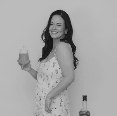 Woman wearing patterned dress smiling and holding drink