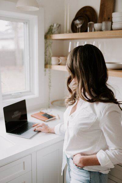 Website copywriter Erika Fitzgerald standing next to a laptop and notebook during a website copy audit working session