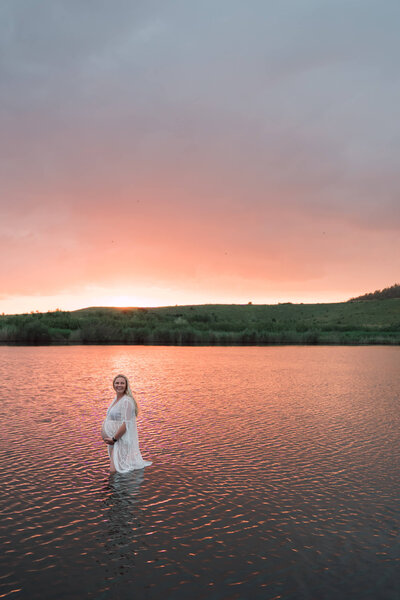 Zwangere vrouw in water met de avondzon