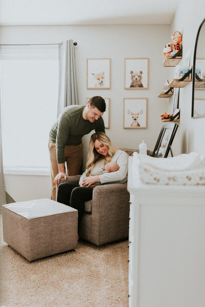 Mom, dad, and newborn baby in a cozy nursery during a professional photoshoot in Minneapolis, captured by Shannon Kathleen Photography, showcasing tender family moments.