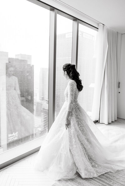 Bride stands in a wedding dress looking out at the Manhattan skyline before her Rockefeller Center Wedding