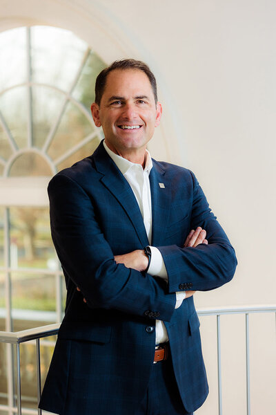 A man in a suit smiling with his arms crossed