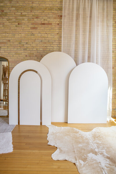 Three large white wooden arches side by side, one with a rainbow cutout.