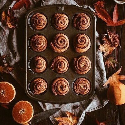 pan of cinnamon rolls with grapefruit and leaves sitting on a table