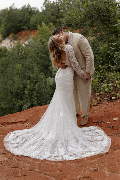Eloping groom admires his bride as they share a loving moment surrounded by breathtaking red rock.