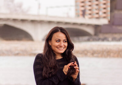 Ana Tamez braiding her hair, and smiling to the side, this photo was taken in Downtown Calgary, Alberta , Canada, you can appreciate on the background a little of the frozen river with snow in it.