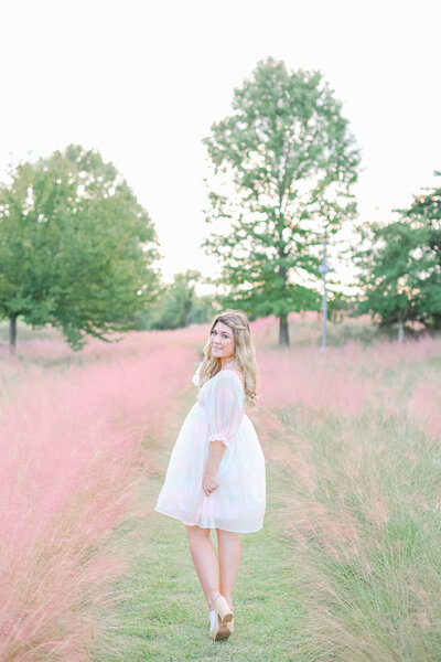 Abby Bell, a fine art portrait photographer in Alabama, standing in a picturesque pink field. Abby Bell Photography specializes in luxury, personalized, and timeless wedding and portrait photography, offering romantic and memorable experiences for couples and individuals across Alabama.
