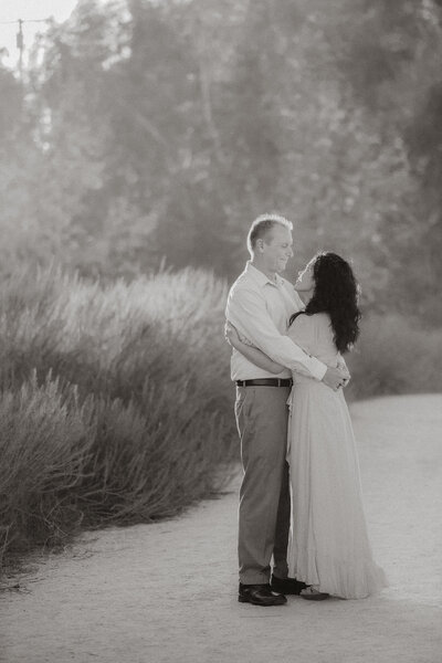 Black and white photo of a couple embracing in the scenic Seal Beach trails, Southern California.
