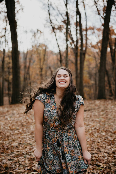 Photo of Kaitlin of Kaitlin Powell Photography laughing and dancing in the fall leaves. Photo taken by Rachel Rowland. 