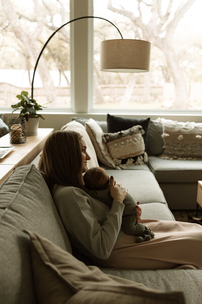 mom holding newborn on her couch in the living room
