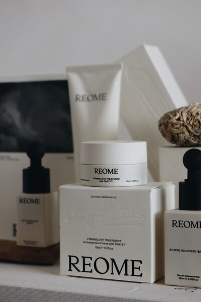 Coloured close-up of various Reome skincare products arranged in a neat, minimalist display, featuring a firming eye treatment and an active recovery serum.