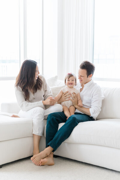 Family with toddler on couch smiling at Indoor lifestyle NYC  family session