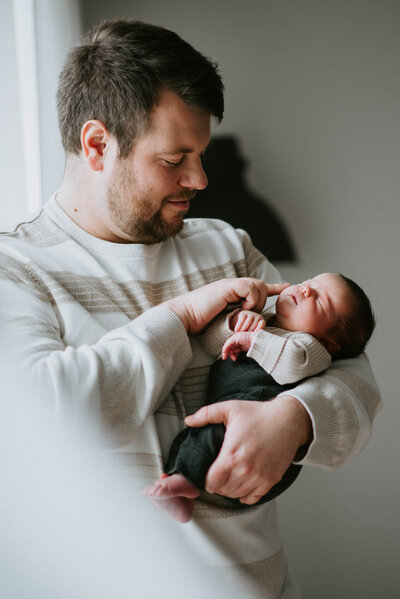 Ein Vater hält sein neugeborenes Baby im Arm beim Foto Shooting