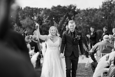 A groom and a bride happily cheer and celebrate as they walk down the aisle after their wedding ceremony. Photo taken by Cleveland Wedding Photographer Aaron Aldhizer