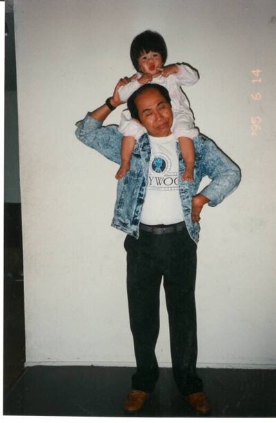 Susan Ly as a baby sitting on her dad's shoulders in an old nostalgic film camera