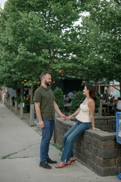 The couple shares a tender embrace at Grand Haven Beach during golden hour, bathed in the warm, soft light of sunset, creating a romantic and intimate moment against the picturesque beach backdrop.
