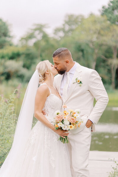 Bride and groom kissing in front of a lake