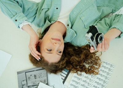Haylee Harris laying on the ground, looking off to the side with her hand in her hair.