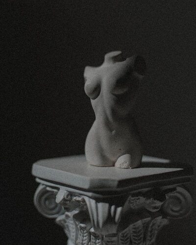 A dramatic photo of a miniature sculpture on a pedestal 