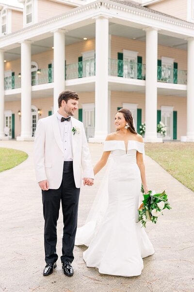 sophisticated bride and groom walk down path in front of Birmingham wedding venue