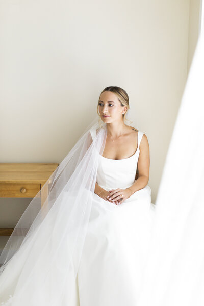 bride sitting in wedding gown after getting hair and makeup done