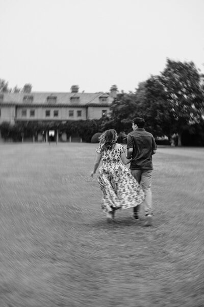 Couple running in a field in front of Eolia mansion at Harkness Memorial State Park in Connecticut