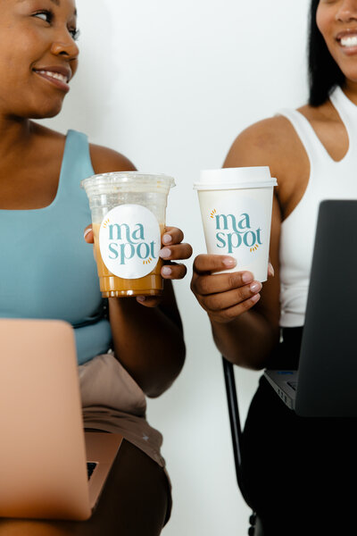 women holding coffee and on computers