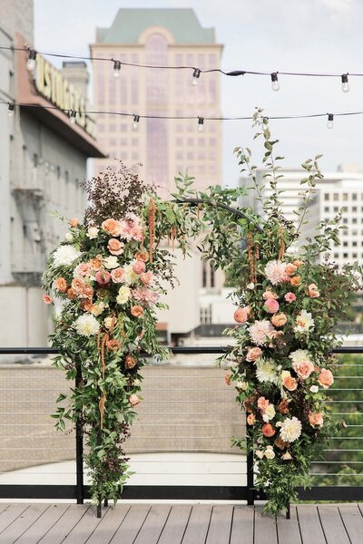 pink, orange, and yellow floral arch setup on the roof at vista overlooking downtown milwaukee skyline
