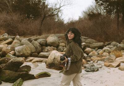 Photographer holding camera on rocky beach