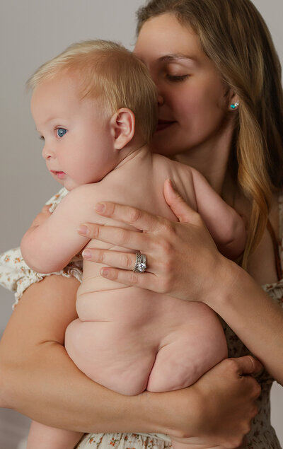 A mother holding her newborn baby against her chest during a lifestyle photography session.