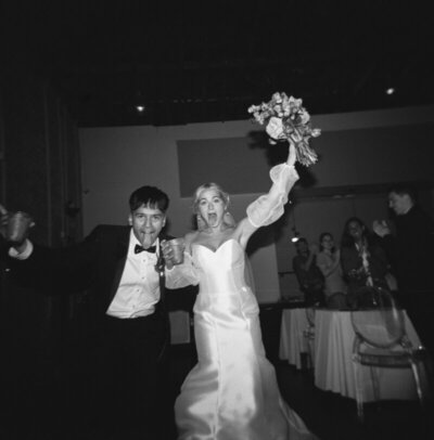 Bride and groom cheering black and white image by best candid wedding photographer Noble Photo Co